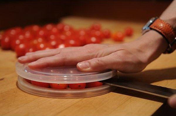 Cut small foods like cherry tomatoes by using two plastic lids.
