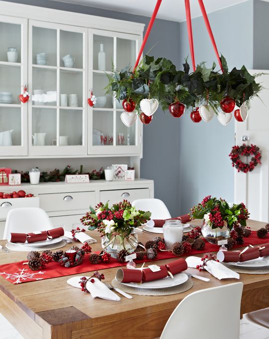 A red and white Christmas chandelier, a red table runner and berries for decor.