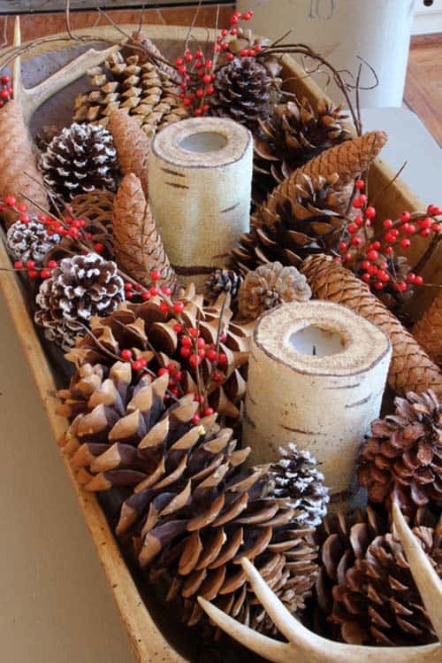 Large dough bowl filled with a mix of pine cones, berries, antlers and candles.